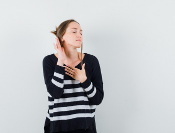 young-woman-standing-listening-pose-holding-one-hand-chest-while-closing-eyes-striped-knitwear-black-pants-looking-happy-2-_main